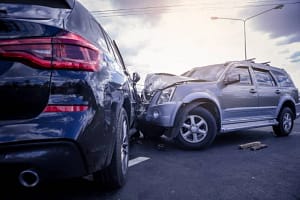 Car crash head on collision between black and gray cars on road