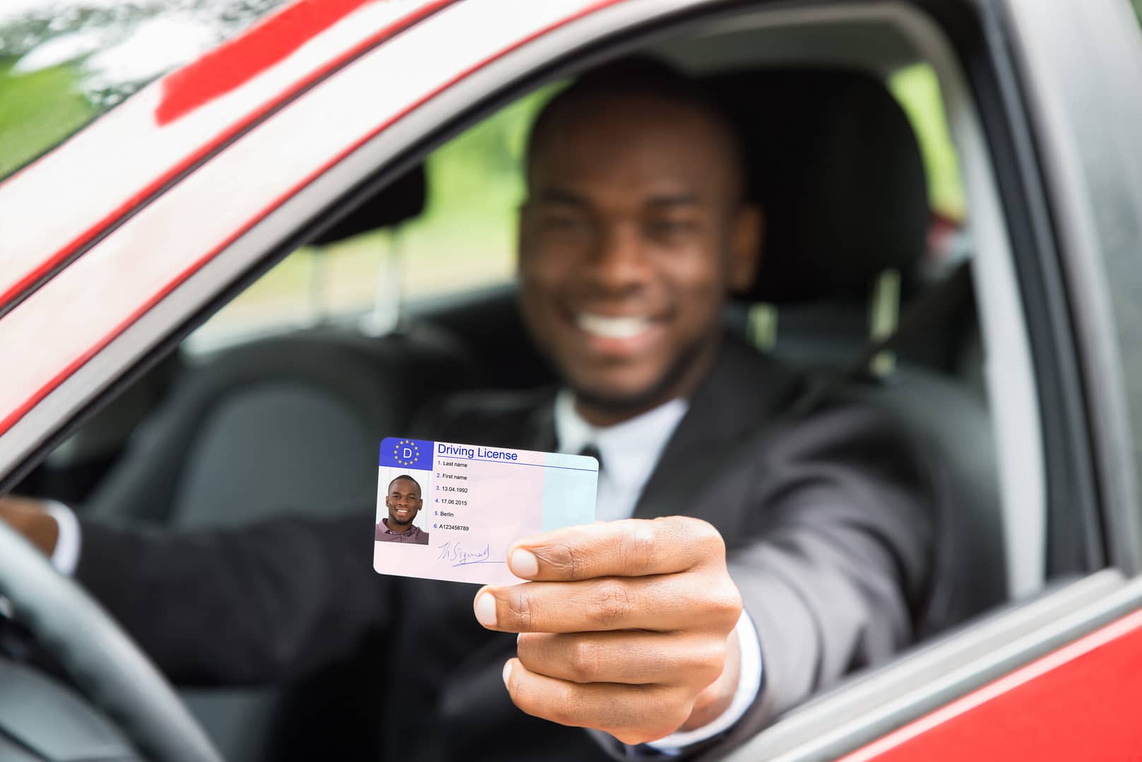 Driver license shown by man from open car window AdobeStock 116906731 scaled