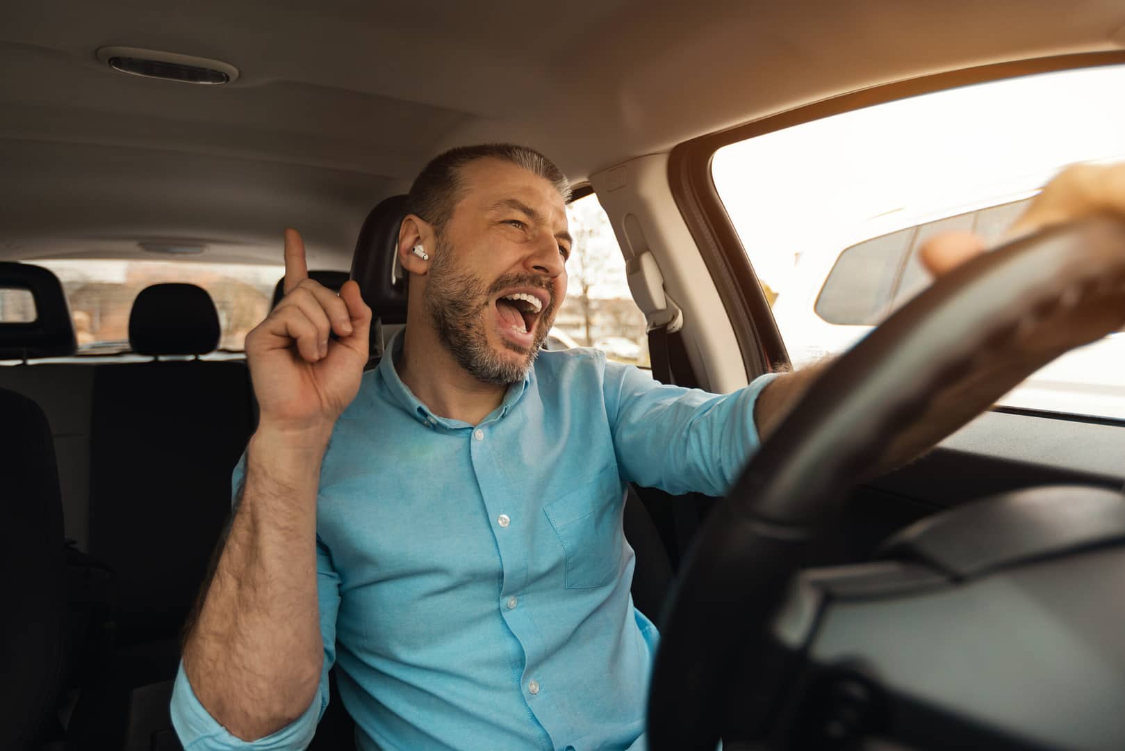 Man driving a car with wireless earphones