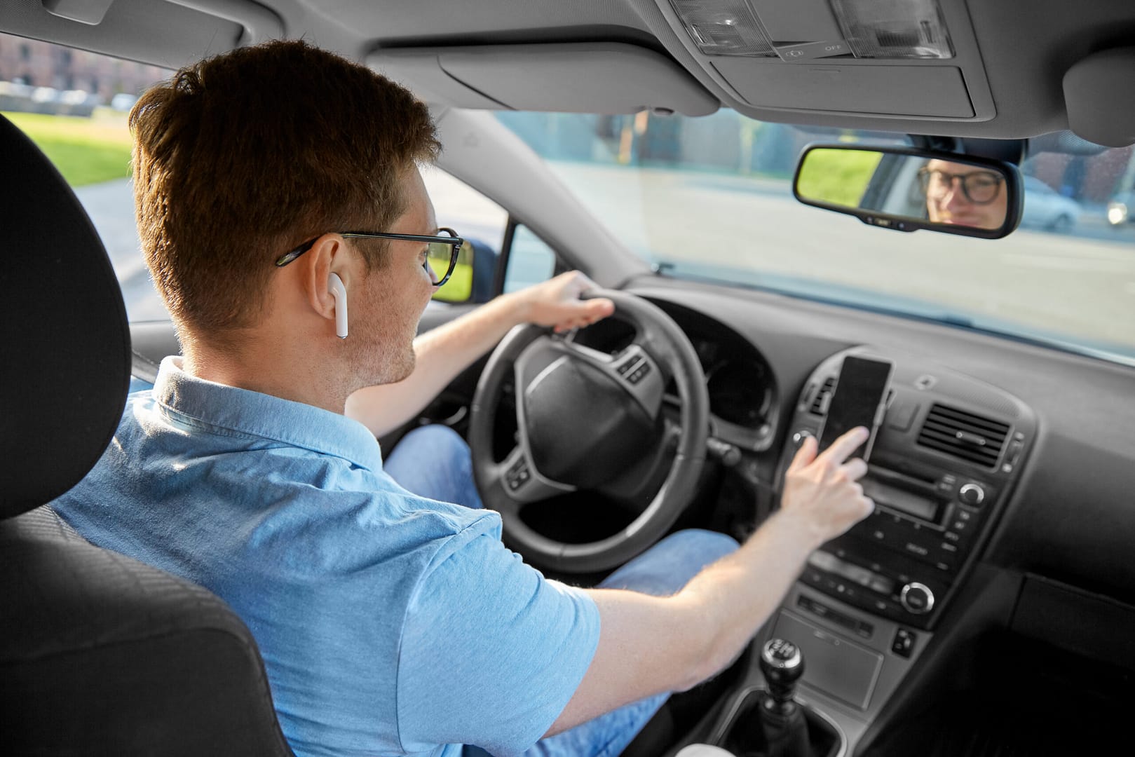 Hombre conduciendo un coche y usando GPS en un teléfono inteligente