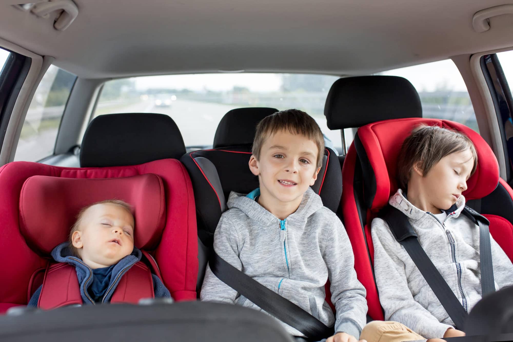 Three young kids in the car backseat