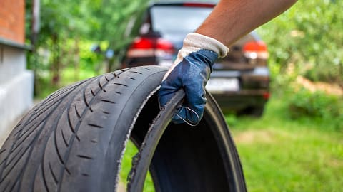 Man holding a defective tire that has de-treaded - Product Liability Lawyers