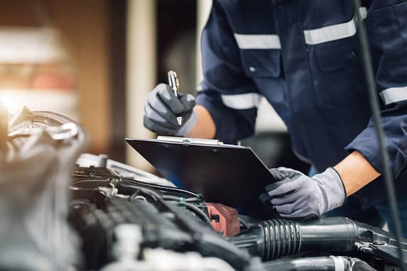Mechanic works on the engine of the car in the garage. Repair service. Concept of car inspection service and car repair service. Texas vehicle inspection laws.