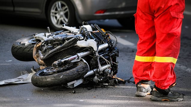 Un socorrista médico de pie junto a una motocicleta destrozada. Estadísticas de accidentes de motocicleta en San Antonio, Texas.