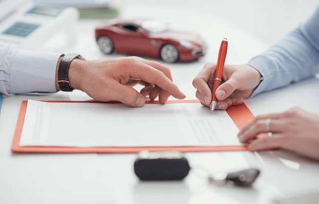 Driver signing a car insurance document