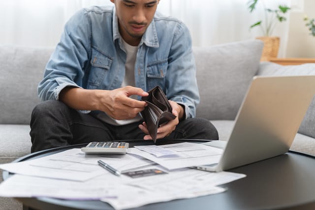 Young man opening empty wallet stress to find money to pay debt mortgage due to lost wages from a personal injury claim.