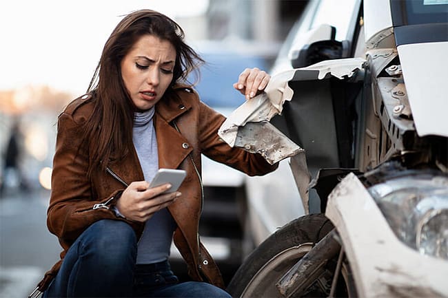 Mujer mirando su teléfono después de un accidente automovilístico - Abogado de accidentes de viaje compartido de Dallas