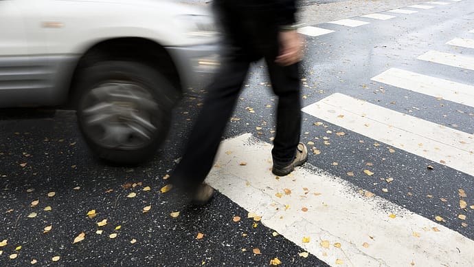 Hombre caminando por un cruce de peatones a punto de ser atropellado por un automóvil - Abogados de accidentes de peatones en Waco Texas