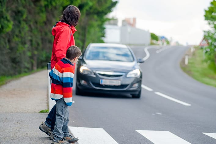 Woman and child crossing the street in a crosswalk while a car is approaching - Waco pedestrian accident lawyers