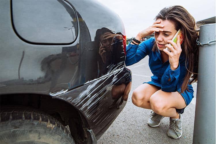 Mujer en teléfono sobre reclamación de daños a la propiedad de accidente de coche