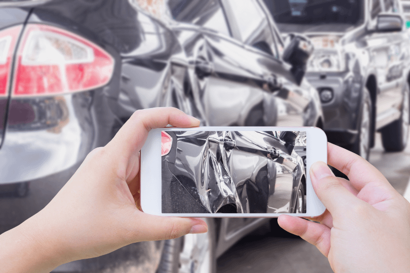 Hand using mobile smart phone taking photo of the car crash accident damage for insurance. Personal Injury Lawyer