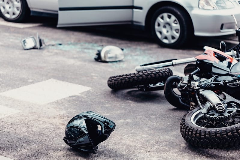 Helmet and motorcycle next to broken peaces of a car on the street after car crash. Injuries motorcycle accidents. Grand Prairie Motorcycle Accident Lawyer. Corpus Christi Motorcycle Accident Lawyers. Corpus Christi Motorcycle Accident Lawyer