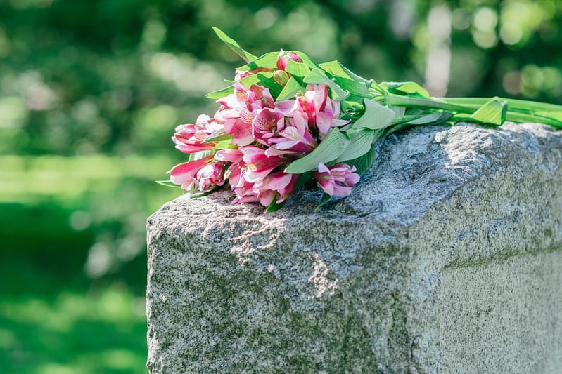 Headstone in cemetery with flowers for concept of death and loss