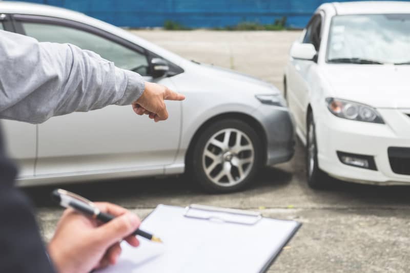 Un hombre señala un accidente automovilístico mientras otro toma notas. Determinar la culpa en un accidente automovilístico en Texas.