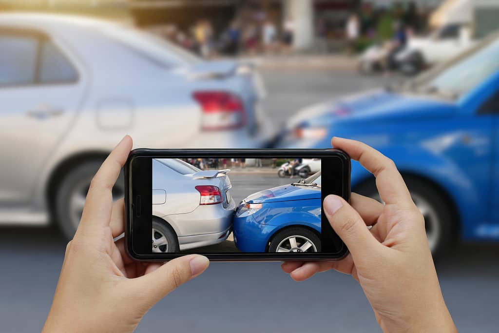 Close up hand holding smartphone and take photo at The scene of a car crash and accident, car accident for car insuranc claim. Car accident