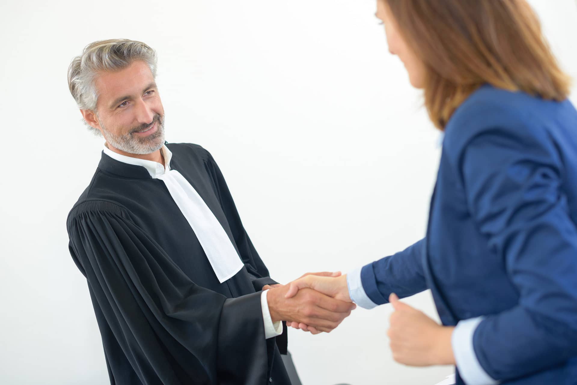Legal worker in robes shaking hands with woman in suit. Legal counsel